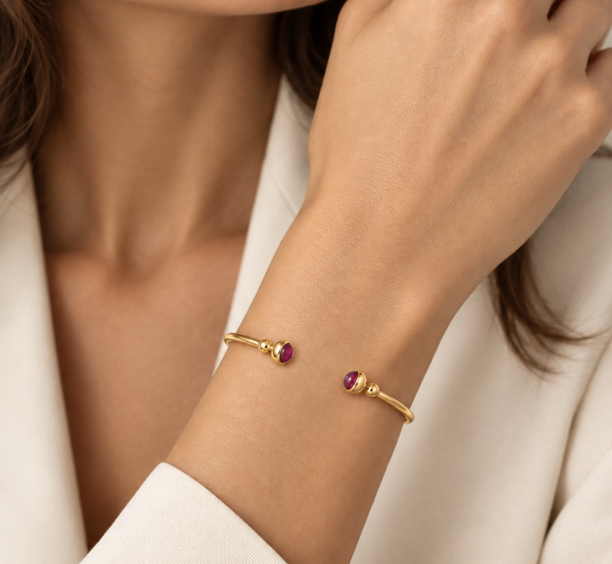 Poignet fin portant un bracelet jonc ouvert en or jaune 18 carats serti de deux rubis naturels, un bijou élégant conçu pour ne pas tourner.