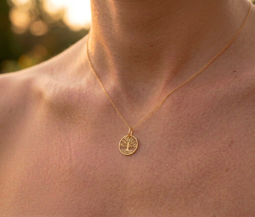 Gros plan sur une femme portant le pendentif Arbre de Vie en or jaune 18 carats, modèle ajouré de 18 mm avec détails de branches et racines.
