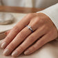 Bague de luxe avec motif croix en or blanc et pierres précieuses portée par une femme, style élégant.