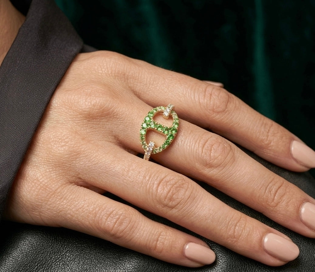 Bague chaîne d'ancre maille marine en or jaune 18 carats, pavée de grenats verts et de diamants portée par une femme