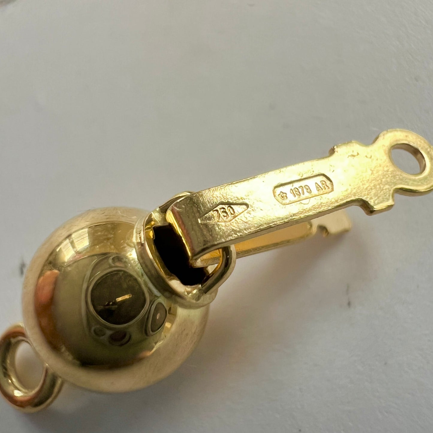 fermoir perle de sécurité rond en or jaune 18 carats, montrant son mécanisme à cliquet.