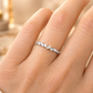 Gros plan sur une main de femme portant une alliance originale en or blanc 18 carats, modèle demi-tour serti de diamants baguettes et ronds.