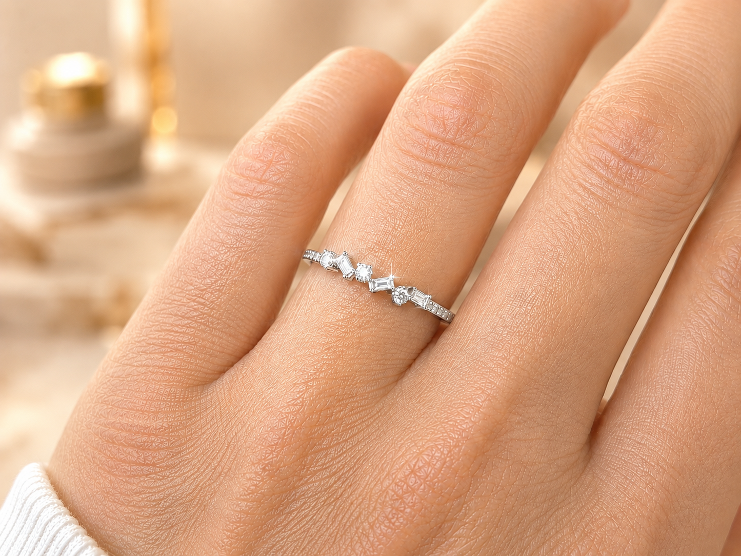 Gros plan sur une main de femme portant une alliance originale en or blanc 18 carats, modèle demi-tour serti de diamants baguettes et ronds.