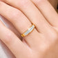 Alliance de mariage en or jaune 18 carats avec pavage 3 rangs de diamants portée au doigt d'une femme au soleil.