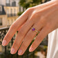 Gros plan sur une main de femme portant une bague solitaire moderne en or jaune 18 carats sertie d'une améthyste cabochon et de diamants étincelants.