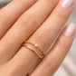 Gros plan sur une main de femme portant une bague chaîne en or 18 carats sertie d'un diamant solitaire, style bijou de peau minimaliste.