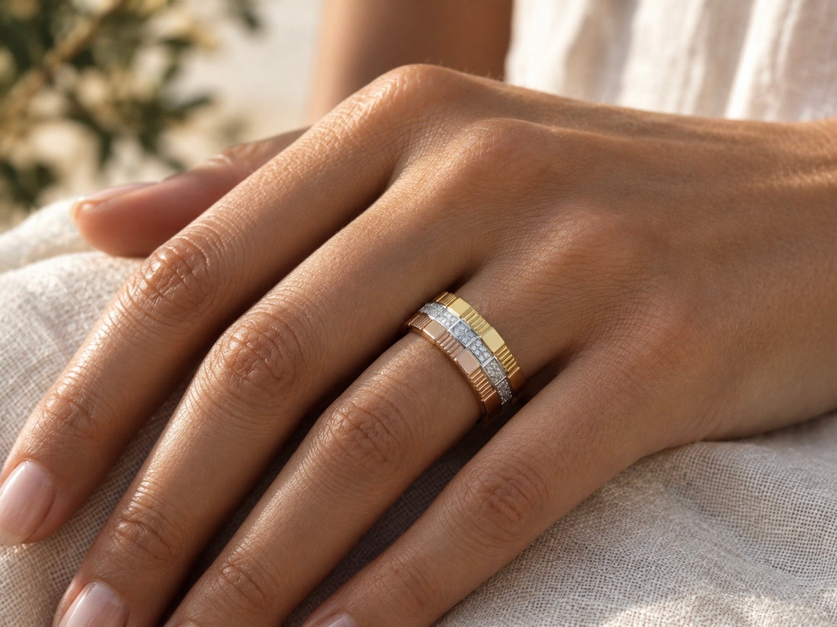 Grosse bague femme 3 ors 18 carats (jaune, rouge, gris) et diamants portée à l'annulaire d'une main au soleil.