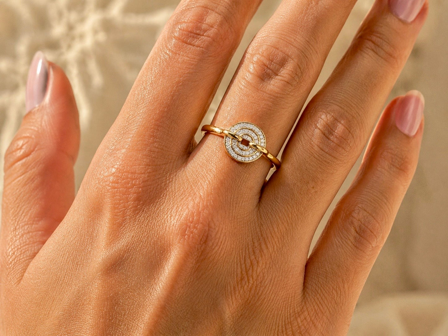 Gros plan sur une main de femme portant une bague disque en or jaune 18 carats avec un pavage de diamants éclatant, design moderne et original.
