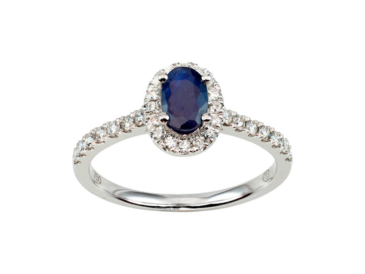Bague de fiançailles en or blanc 18 carats sertie d'un saphir bleu ovale et d'un entourage de diamants brillants.