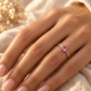 Bague de fiançailles avec saphir rose poire en or jaune 18 carats portée à l'annulaire d'une femme.