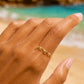 Gros plan sur une main de femme portant une bague en forme de vague en or jaune 18 carats sertie de trois diamants, portée élégamment à l'index.