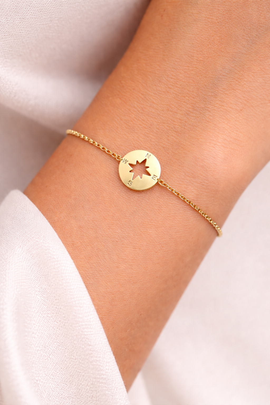 Gros plan d'un poignet féminin portant le bracelet rose des vents en or jaune 18 carats de l'atelier La Fille du Sud.