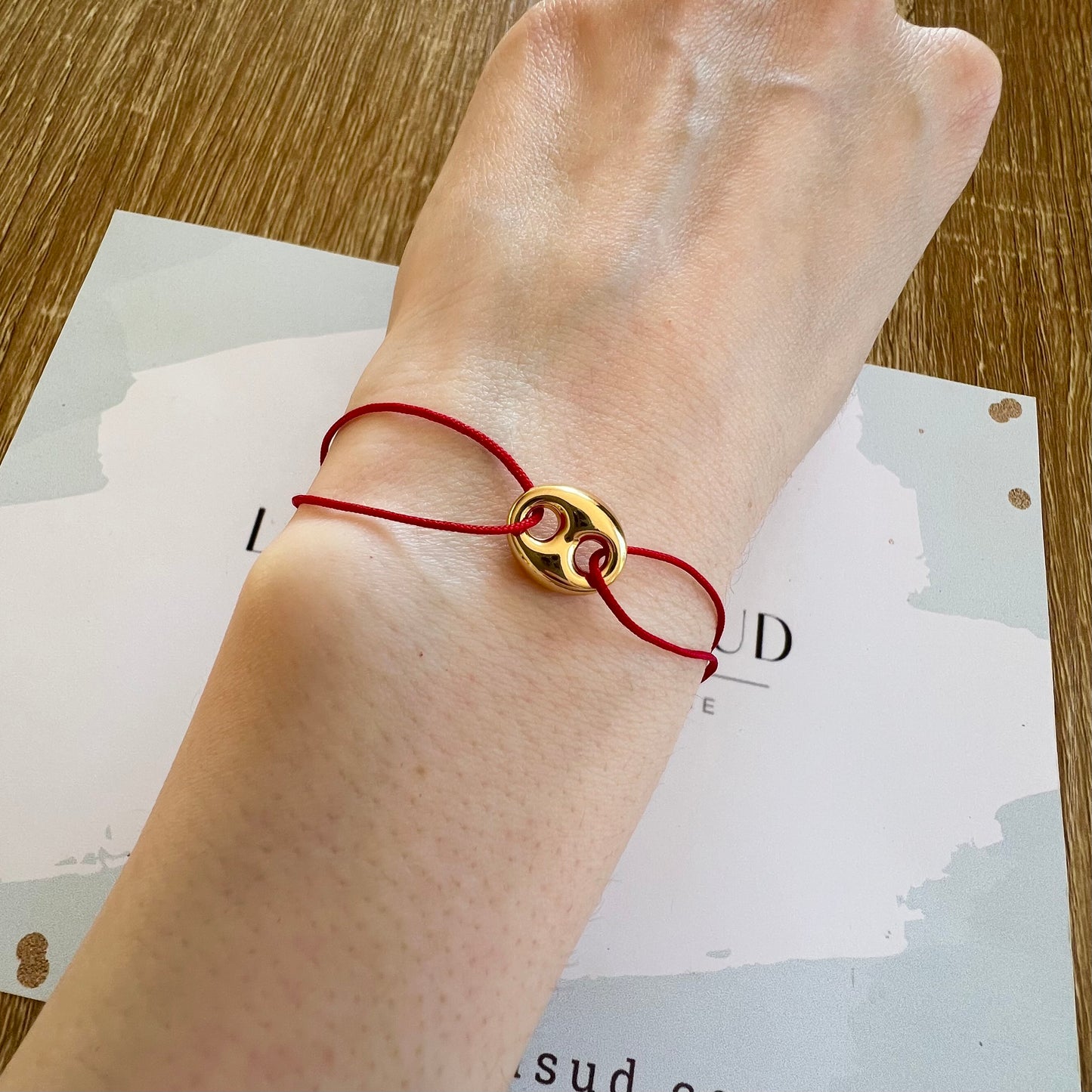 Bracelet cordon rouge porte-bonheur avec un graine de café en or 18 carats.