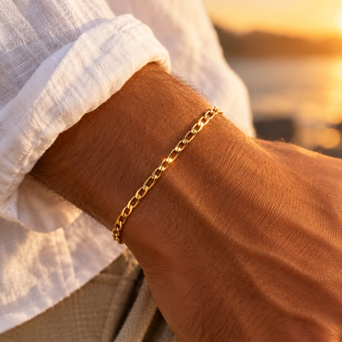 Bracelet maille cheval en or jaune 18 carats porté par un homme élégant en chemise de lin au crépuscule.