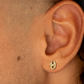 Boucle d'oreille grain de café en or 18 carats portée par un homme, style unisexe et moderne.