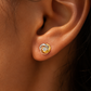 Puces d'oreilles 3 ors 18 carats en forme de nœud portées au lobe sous une lumière solaire.