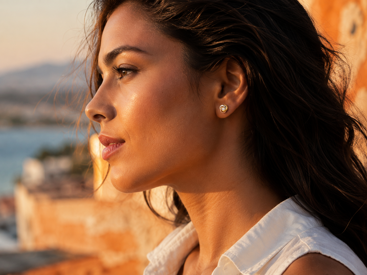 Boucles d'oreilles 3 ors 18 carats en or jaune, rouge et gris portées de profil par une femme au soleil.