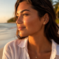 Boucles d'oreilles ananas en or 18 carats portées par une femme à la plage de profil.