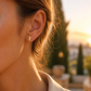Gros plan sur une oreille de femme portant de petites puces d'oreilles cheval cabré en or jaune 18 carats