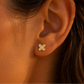 Puce d'oreille papillon en or jaune 18 carats avec oxydes de zirconium portée au lobe d'une femme au soleil.
