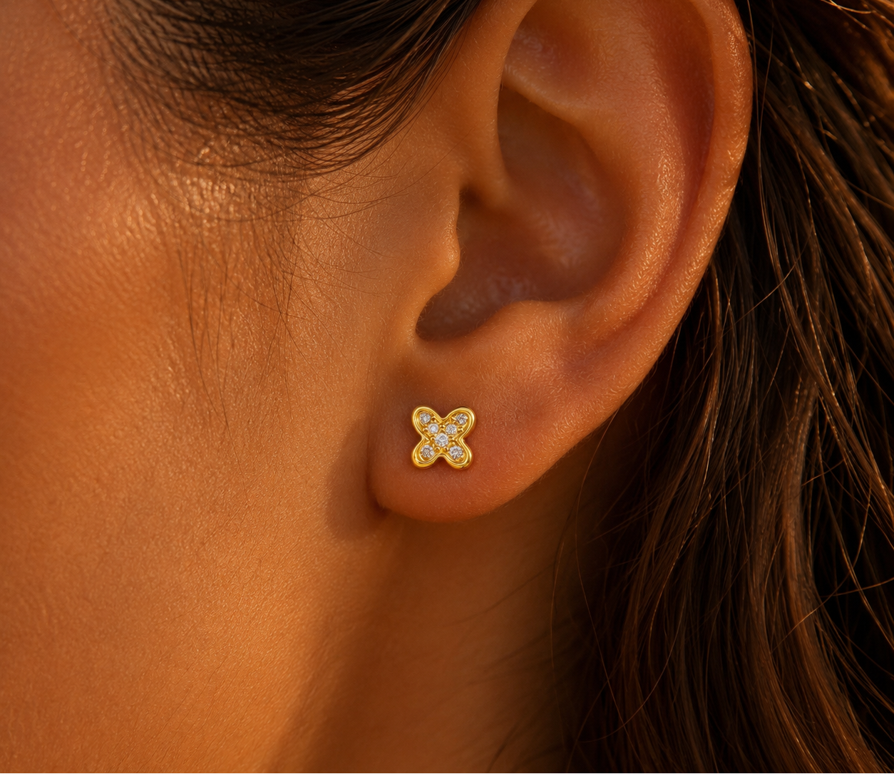 Puce d'oreille papillon en or jaune 18 carats avec oxydes de zirconium portée au lobe d'une femme au soleil.