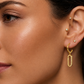Femme portant des boucles d'oreilles pendantes en or jaune 18 carats serties de diamants, motif rectangle évidé moderne.