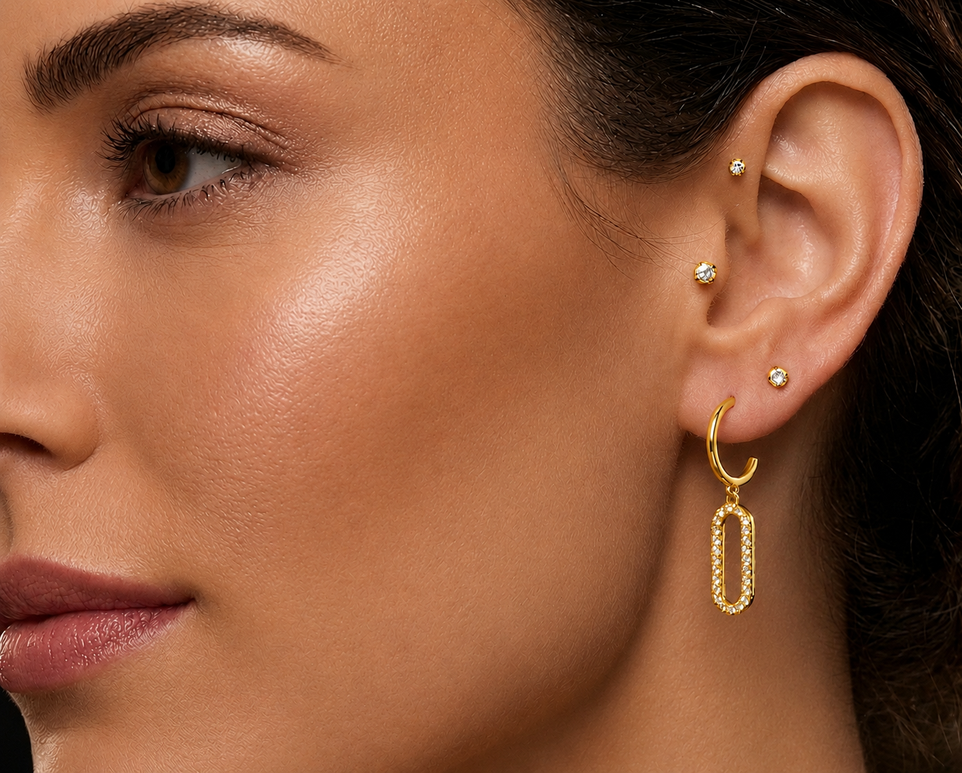 Femme portant des boucles d'oreilles pendantes en or jaune 18 carats serties de diamants, motif rectangle évidé moderne.