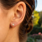 Oreille de femme portant une puce d'oreille en perle de culture ornée d'une étoile en or jaune 18 carats.