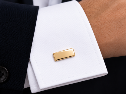 Bouton de manchette rectangulaire en or jaune 18 carats massif porté sur le poignet mousquetaire d'une chemise blanche.