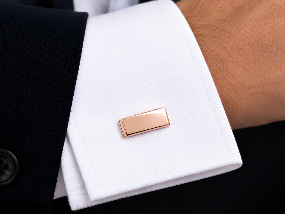 Détail élégant d'un bouton de manchette en or rose 18 carats porté au poignet, un accessoire de luxe idéal pour un costume de marié.