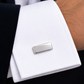 Boutons de manchette minimalistes en or blanc 18 carats portés avec élégance sur une chemise blanche sous une veste de costume.
