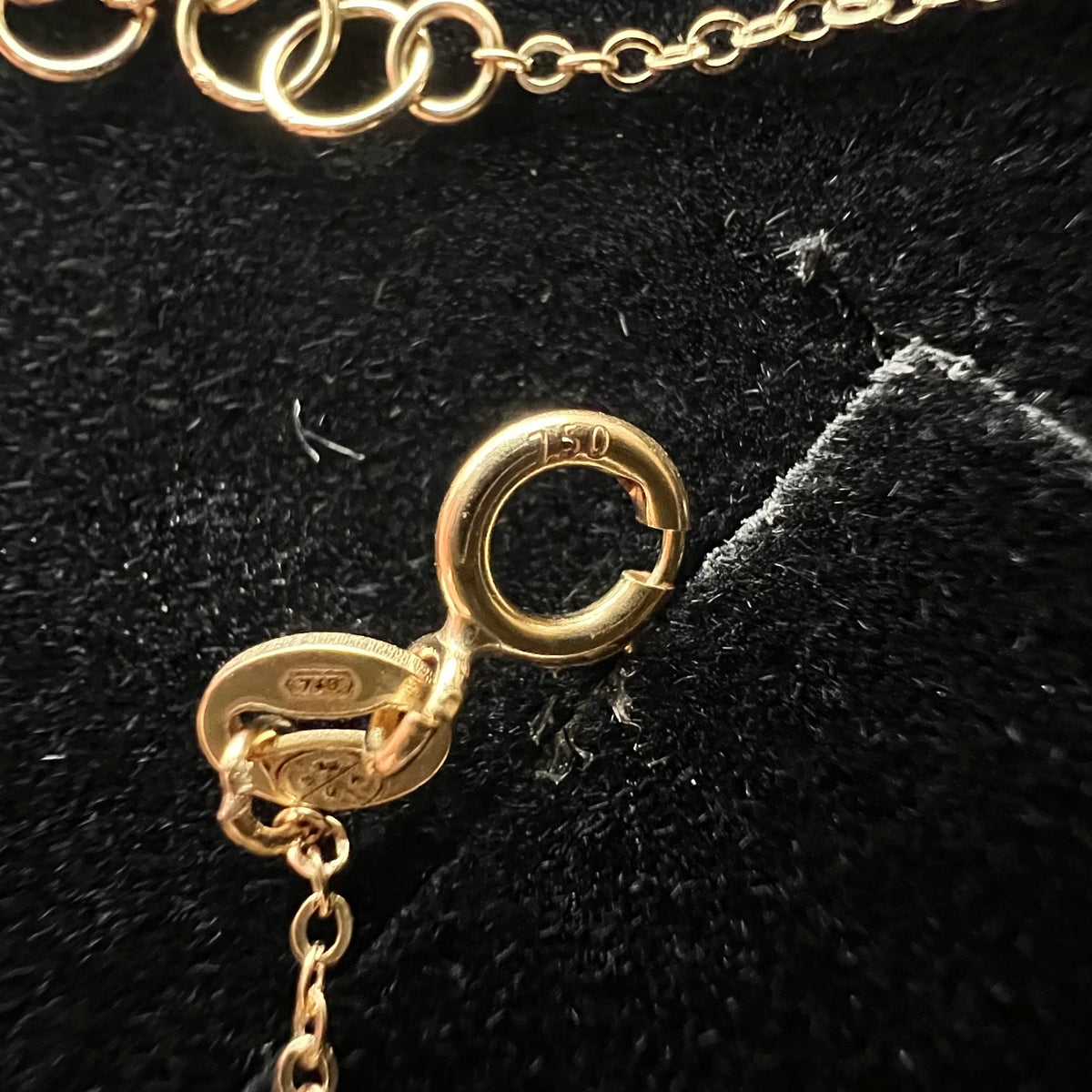 Gros plan sur le fermoir anneau ressort et le poinçon officiel 750 garantissant l'authenticité de l'or 18 carats du bracelet Arbre de Vie.