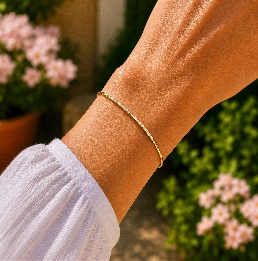 Gros plan sur un poignet de femme portant le bracelet barrette en diamant et or jaune 18 carats, un bijou ajustable à l'éclat solaire.