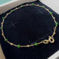 Bracelet en or jaune 18 carats avec boules d'or et résine verte sur velours, gros plan sur le fermoir ressort et le poinçon officiel 750.