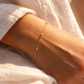 Bracelet chaîne boule en or jaune 18 carats avec petites boules de 1.8mm porté au poignet d'une femme au soleil.