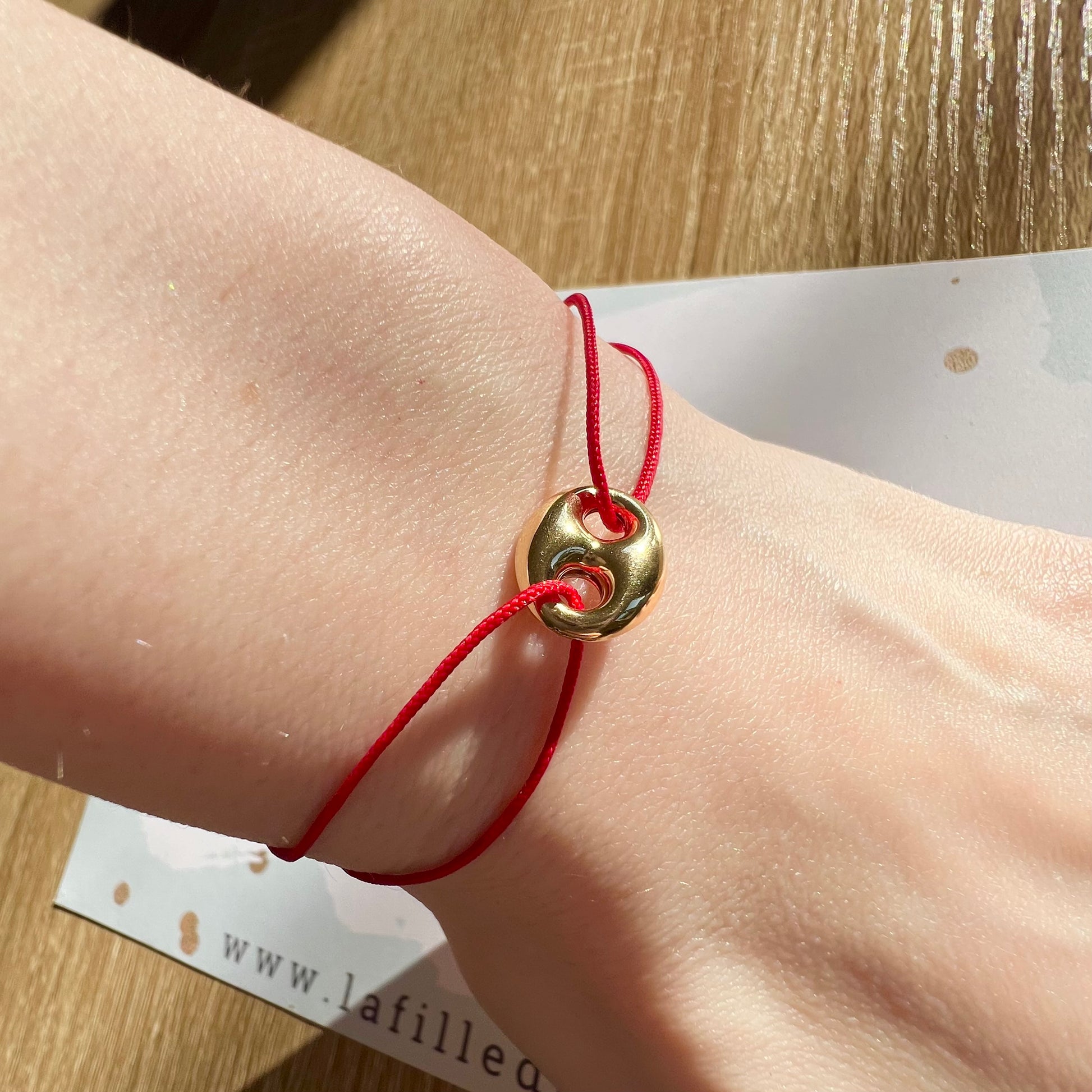 Bracelet cordon rouge porte-bonheur avec un graine de café en or 18 carats.
