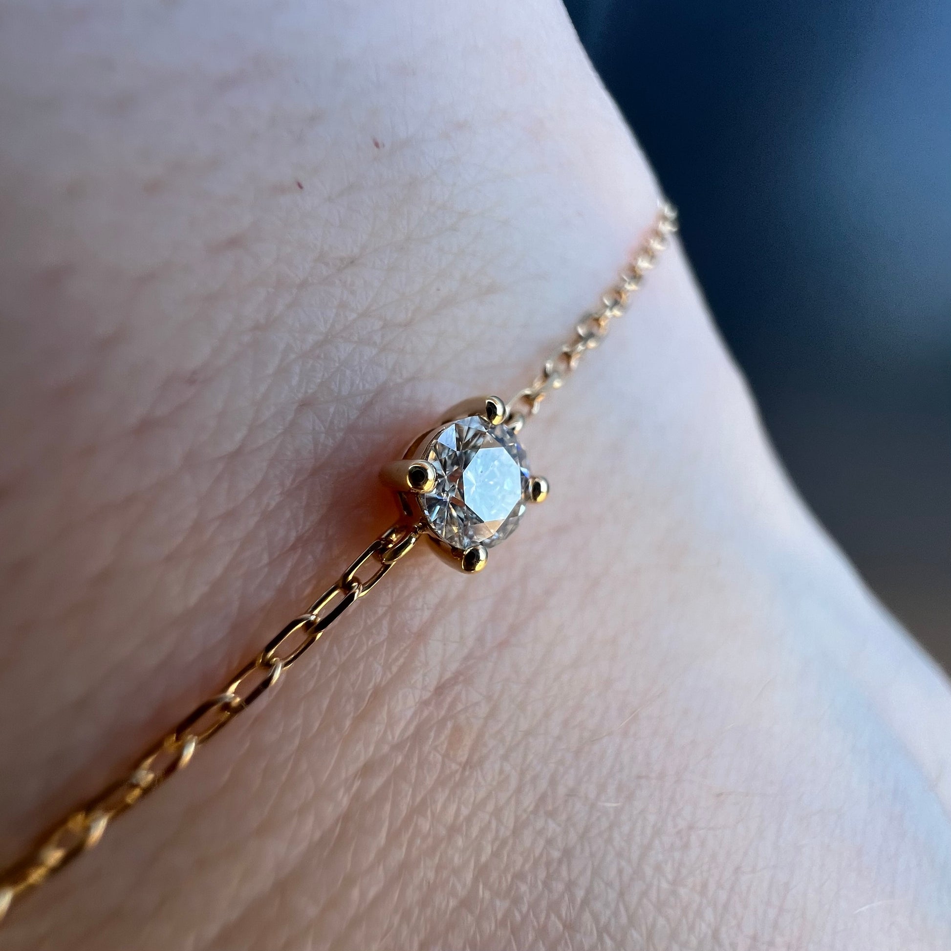 Gros plan sur le serti de ce diamant brillant qui orne un élégant bracelet en or jaune 18 carats porté au poignet