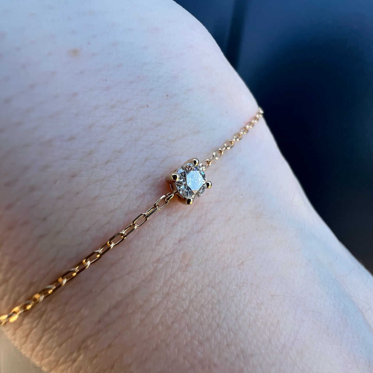 Gros plan sur l'étincelant diamant solitaire de ce bracelet en or jaune 18 carats porté au poignet