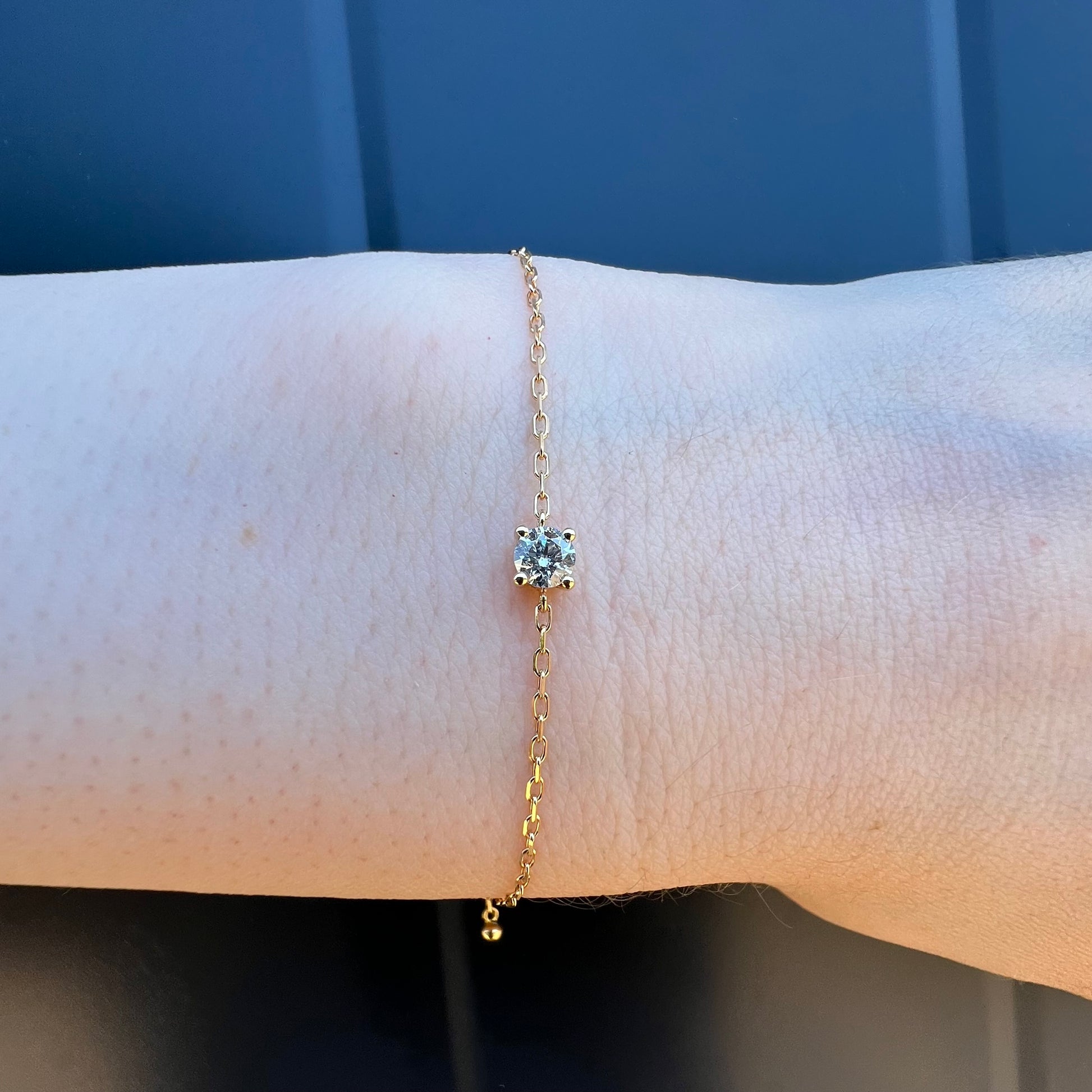 Gros plan sur un élégant bracelet en or jaune 18 carats serti d'un diamant solitaire brillant porté au poignet