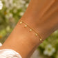 Gros plan sur le poignet d'une femme portant un bracelet étoile en or jaune 18 carats orné de 5 breloques pampilles, style bohème et solaire.
