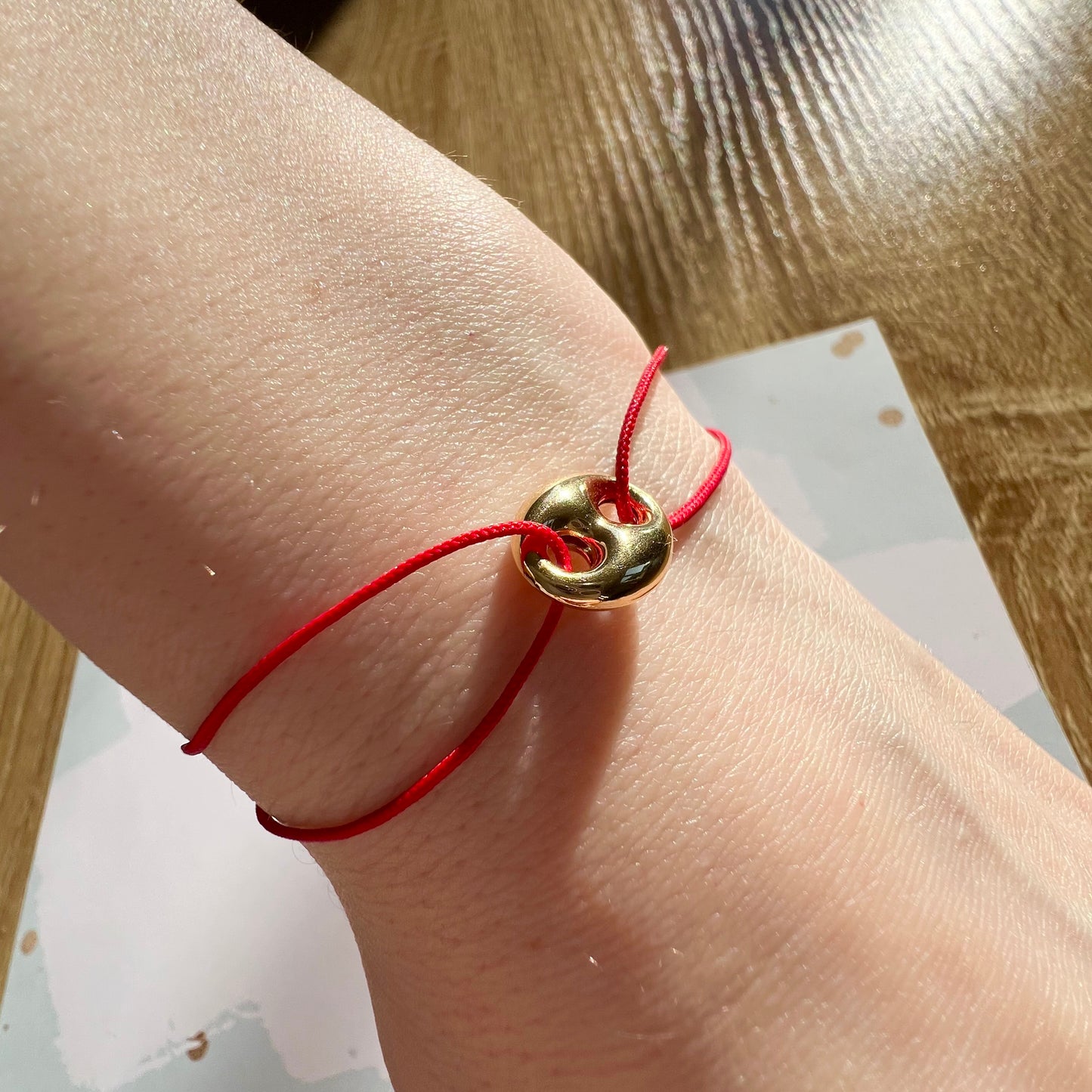 Bracelet cordon rouge porte-bonheur avec un graine de café en or 18 carats.