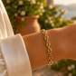 Gros plan sur le poignet d'une femme portant le bracelet grain de café en or 18 carats au soleil couchant.