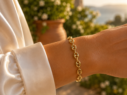 Gros plan sur le poignet d'une femme portant le bracelet grain de café en or 18 carats au soleil couchant.