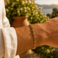 Poignet d'homme portant un bracelet en or jaune 18 carats maille grain de café, style luxe et masculin.