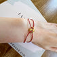 Bracelet cordon rouge porte-bonheur avec un graine de café en or 18 carats.