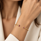 Poignet fin portant un bracelet jonc ouvert en or jaune 18 carats serti de deux rubis naturels, un bijou élégant conçu pour ne pas tourner.