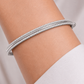 Bracelet jonc rigide en or blanc 18 carats avec double rangée de pierres précieuses porté au poignet
