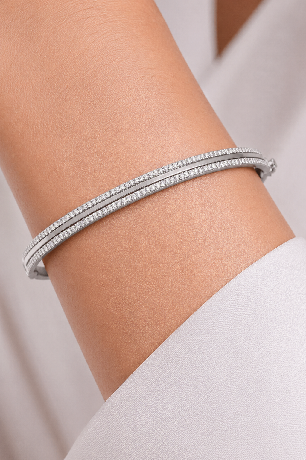 Bracelet jonc rigide en or blanc 18 carats avec double rangée de pierres précieuses porté au poignet