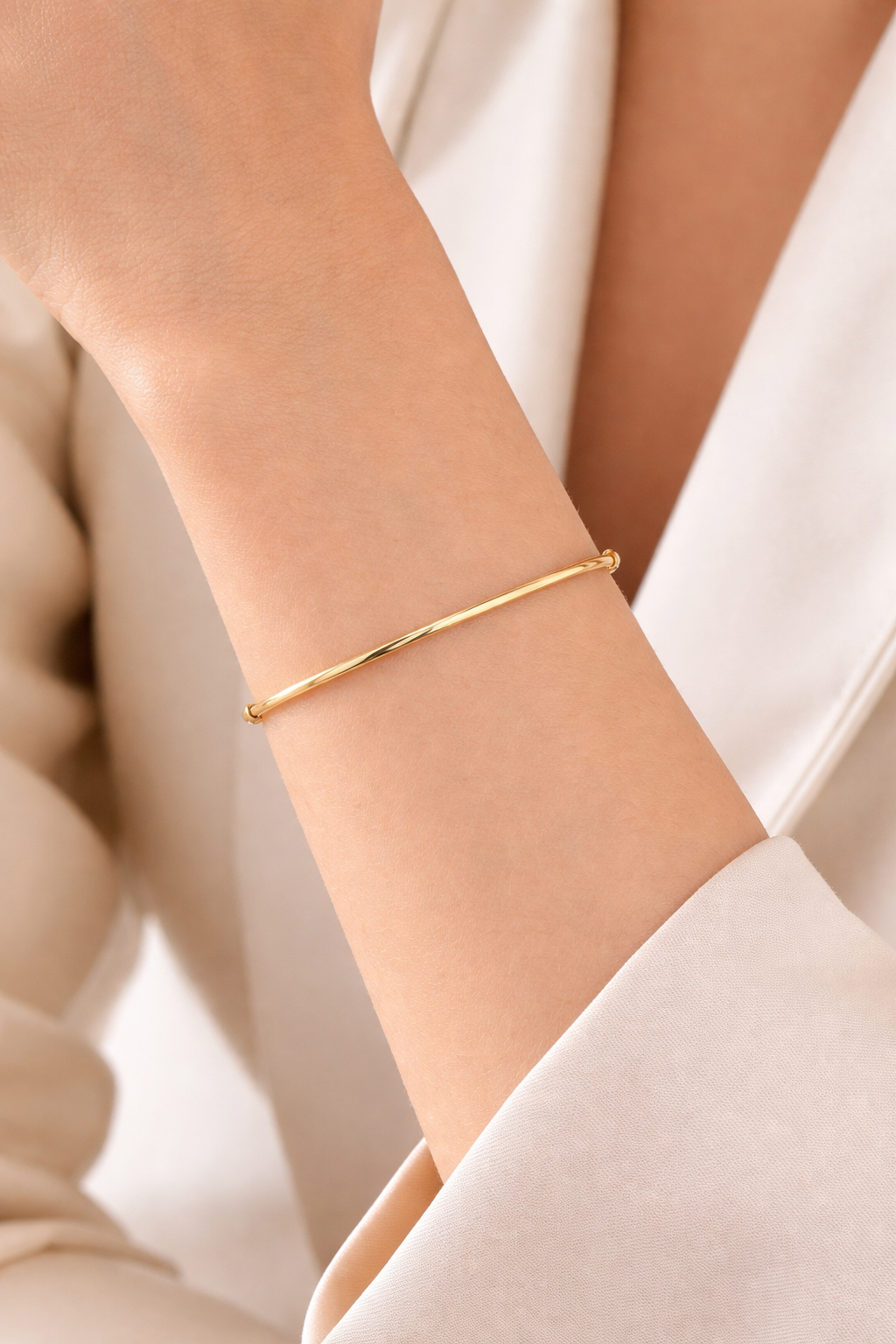 Poignet de femme portant un bracelet jonc articulé fin en or jaune 14 carats