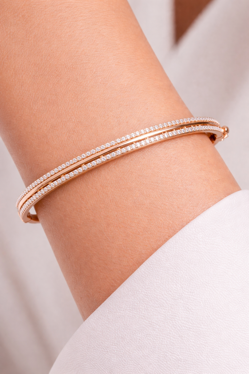 Bracelet jonc rigide en or rose 18 carats serti de deux rangés d'oxydes de zirconium, porté par une femme